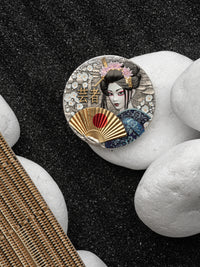 Decorative button with a geisha design on a black and white stone background