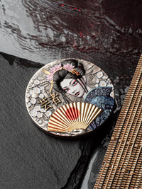 Decorative round object with a geisha design on a textured surface