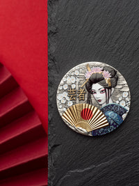 Decorative brooch with a geisha design on a black slate background