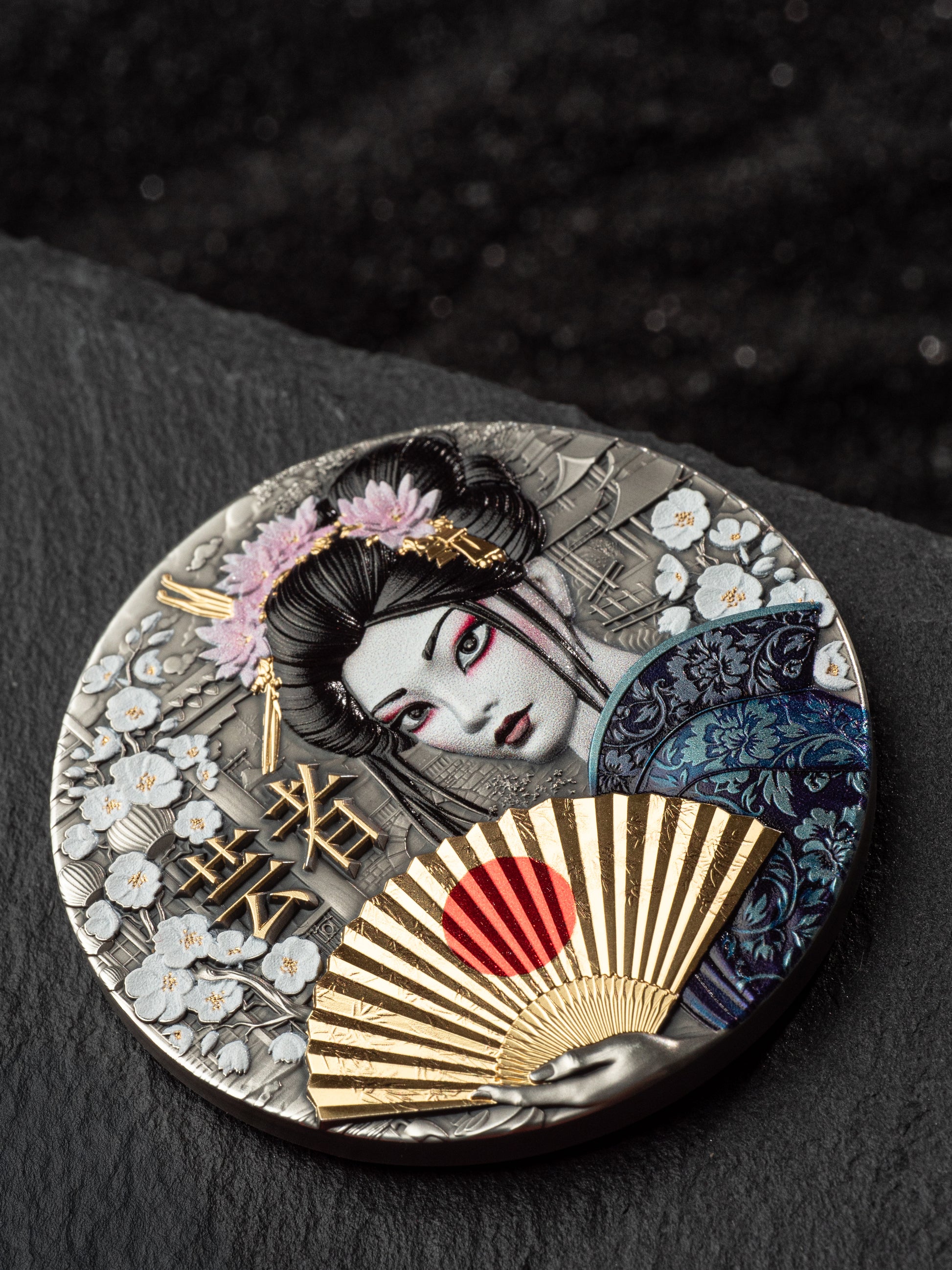 Decorative round object with Japanese-themed design featuring a geisha, fan, and floral elements on a dark background.