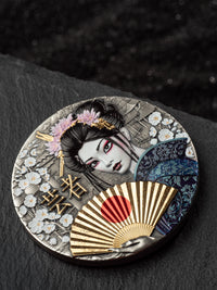 Decorative round object with Japanese-themed design featuring a geisha, fan, and floral elements on a dark background.