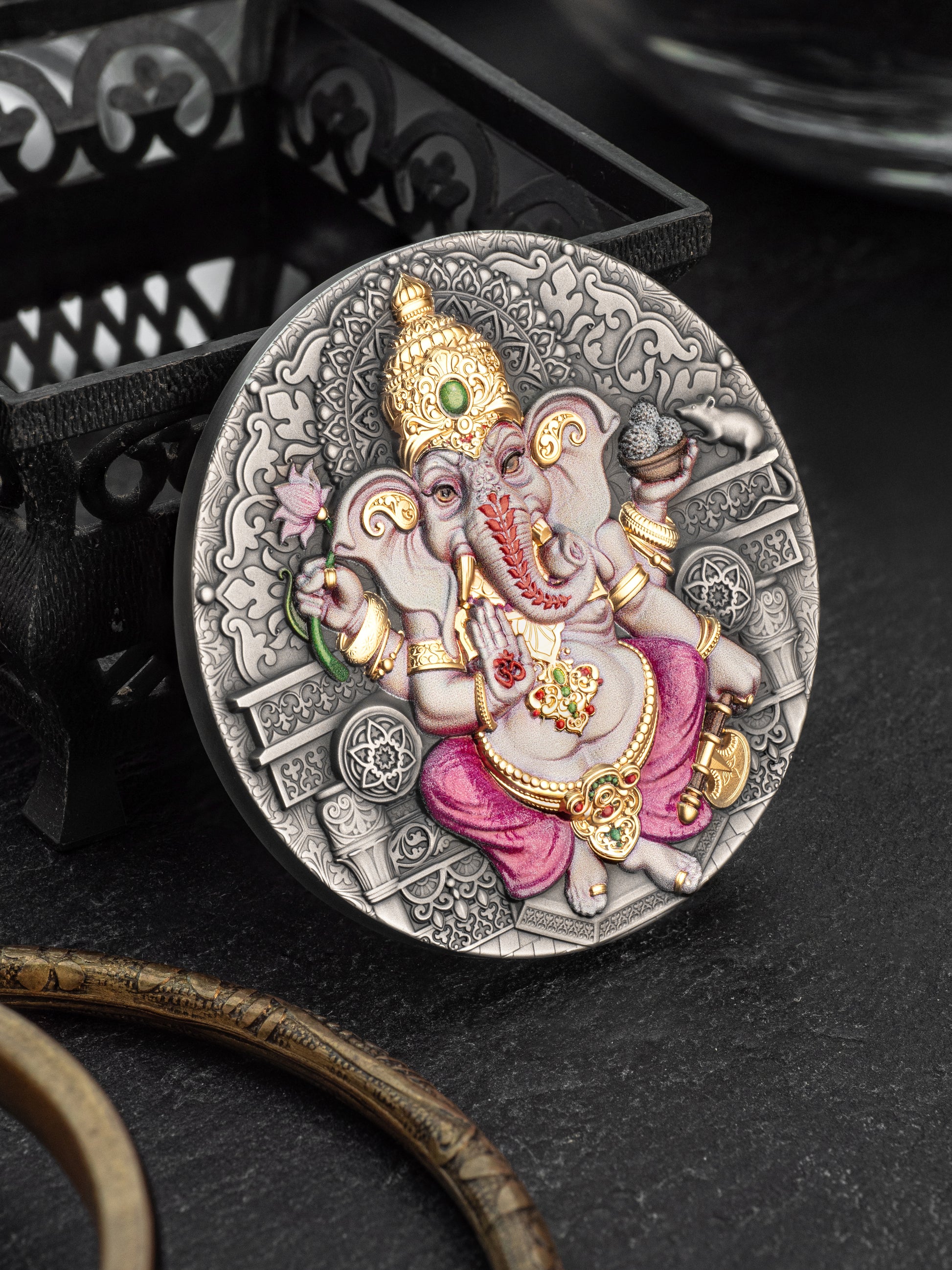 Decorative coin with an intricate design featuring a deity figure on a dark background