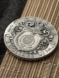 Silver coin with intricate design on a woven surface
