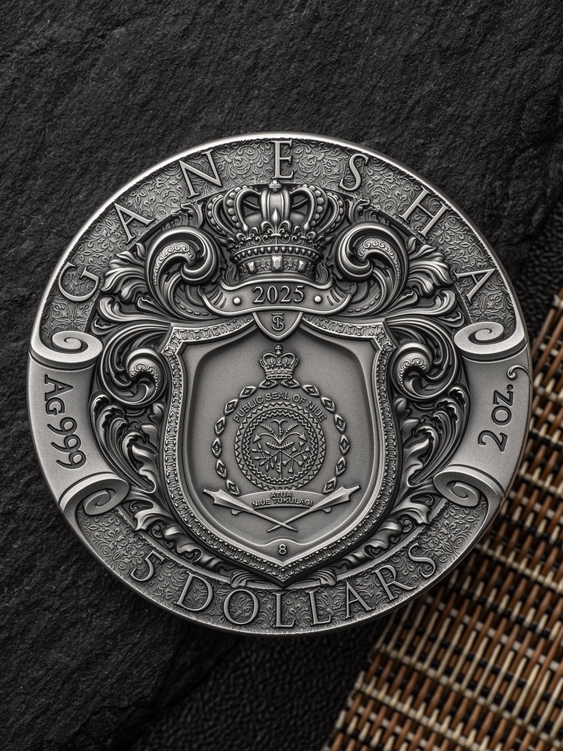 Silver coin with intricate design and text on a textured surface