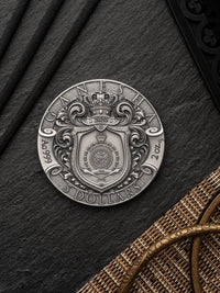 Silver coin with intricate design on a dark surface