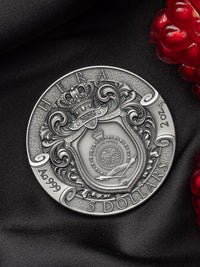 Silver coin with intricate design on a dark fabric background
