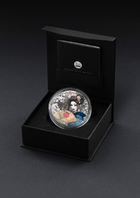 Silver coin with a geisha design in a black box on a dark background