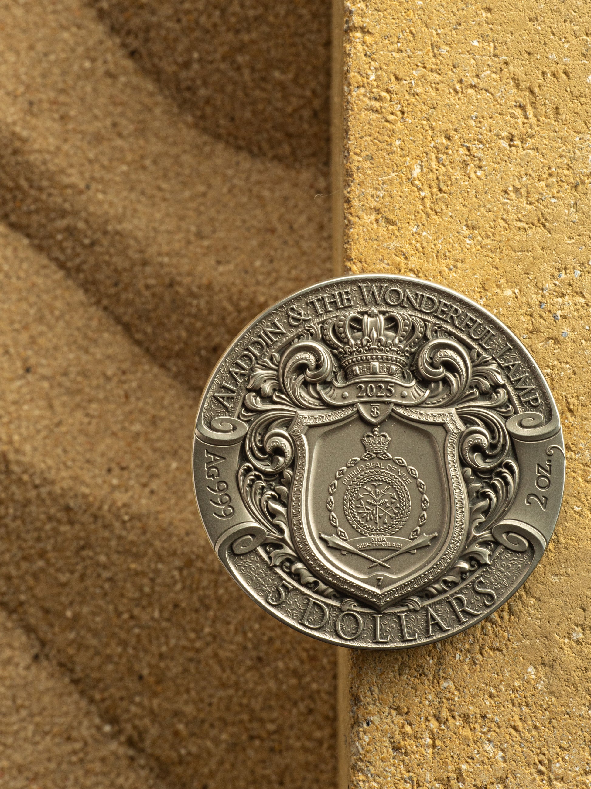 Silver coin with intricate design on a textured brown surface