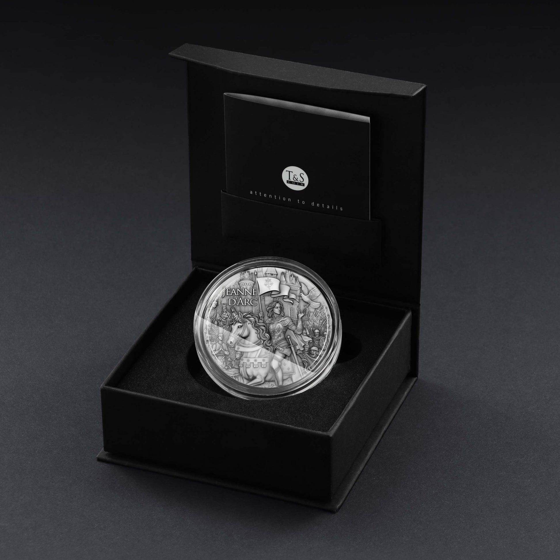 Silver coin with detailed design in a black box on a dark background