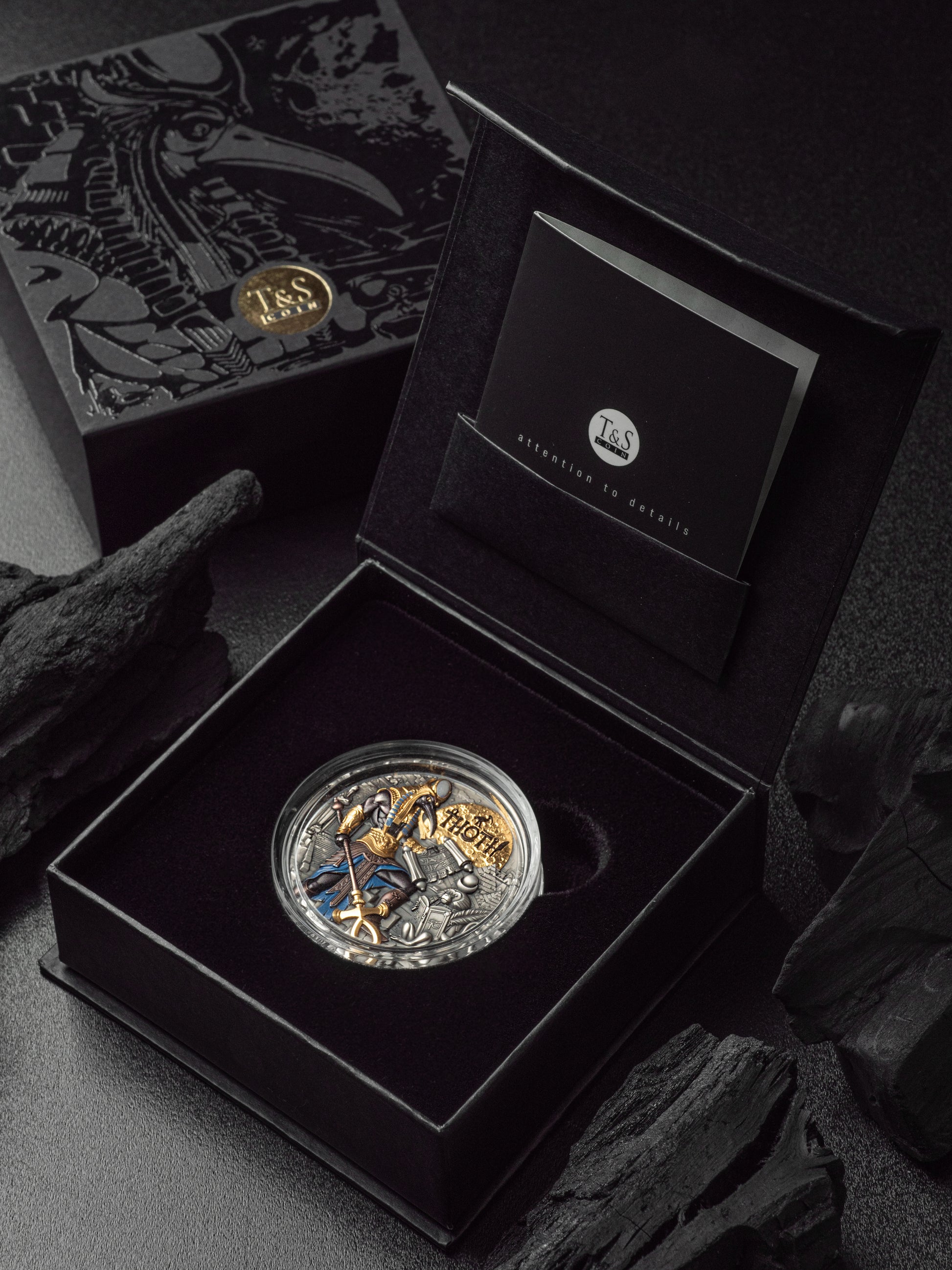 Silver coin with dragon design in an open black box on a dark background
