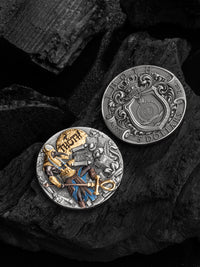 Two metallic coins with intricate designs on a dark stone surface